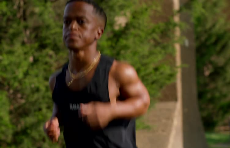 A determined man runs outdoors in daylight focused on his fitness routine