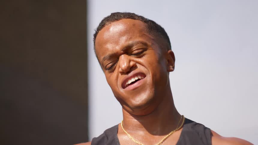A man strains and gasps for breath after intense exercise standing outside in the sun