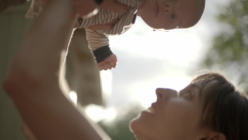A woman holds a baby up in the air