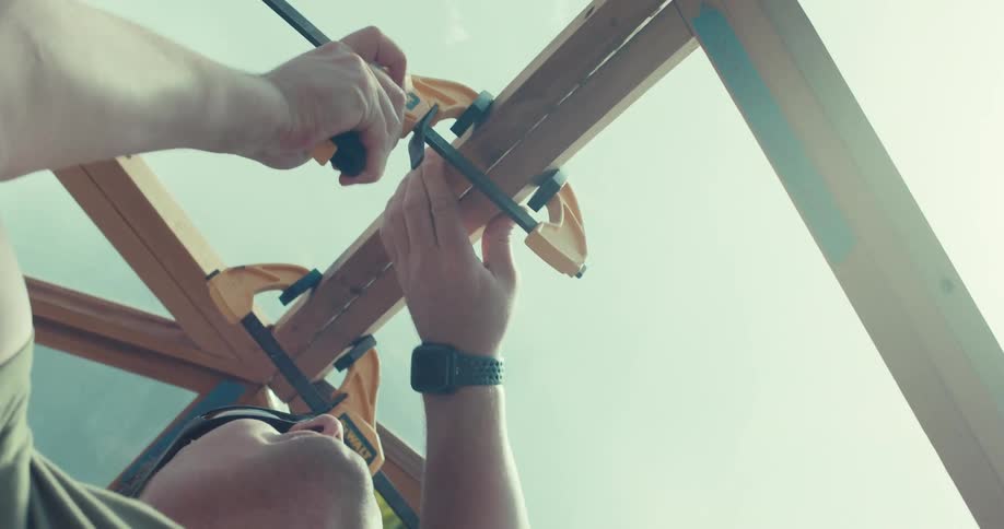 A man wearing sunglasses is working on a building roof at midday