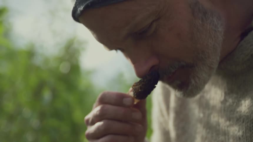 A man smells the plant and smiles