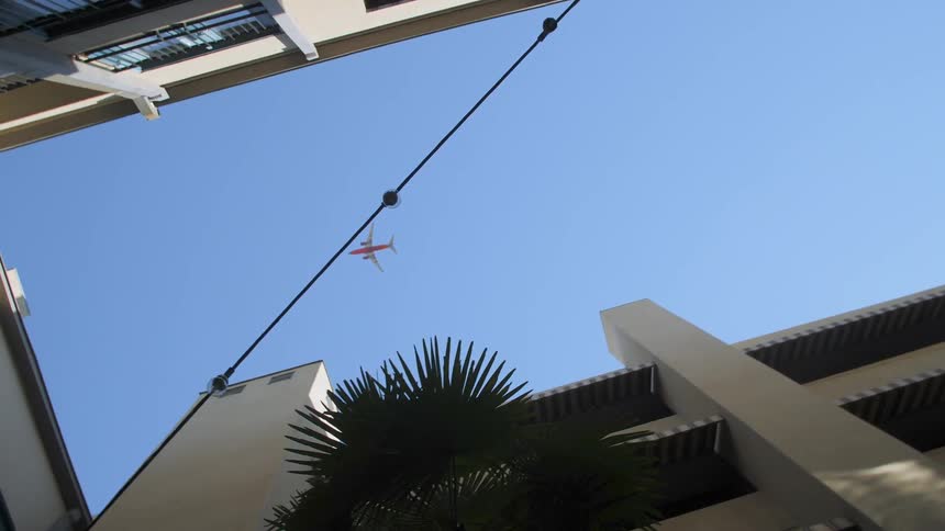 An airplane flies above a building