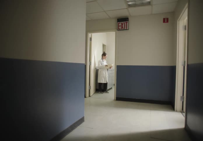 Nurse leaving a hospital clinical room and walking down the hallway