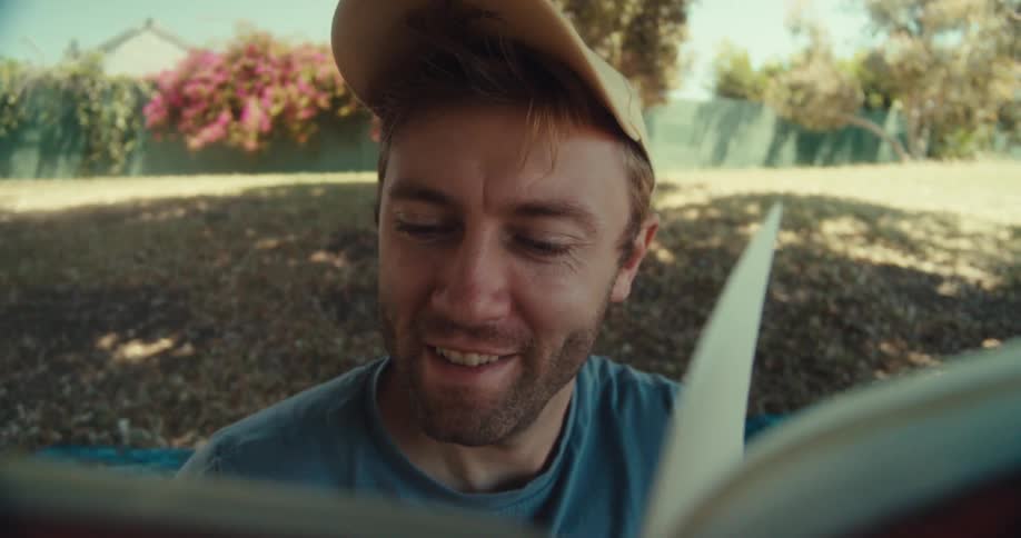 Man in cap lying down while writing on a notepad