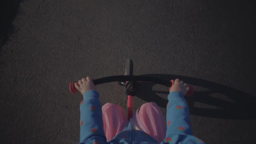 Pair of hands of a child holding the handlebars and riding a bicycle