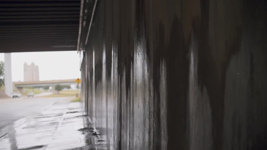 Water pours down the wall under a bridge