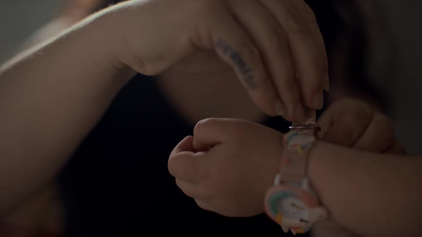 Watch being placed on a childs wrist by an adult