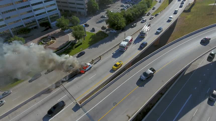 An accident with a car on fire in the middle of a road