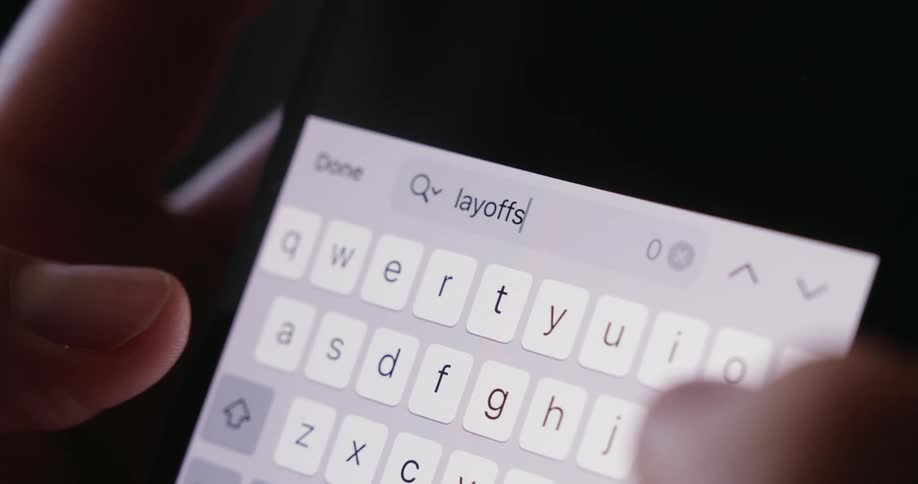 The person types the word layoffs into the phone search engine