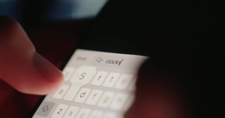 A person typing the word stocks on their phone