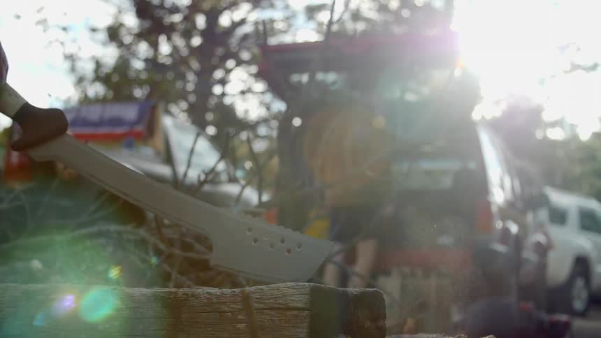 A man hacks a piece of wood with an axe