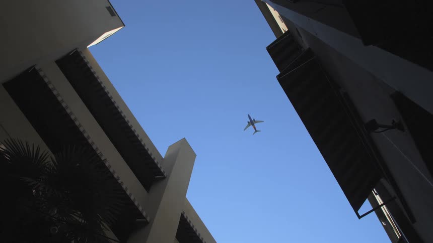 A plane flies over a gap between buildings