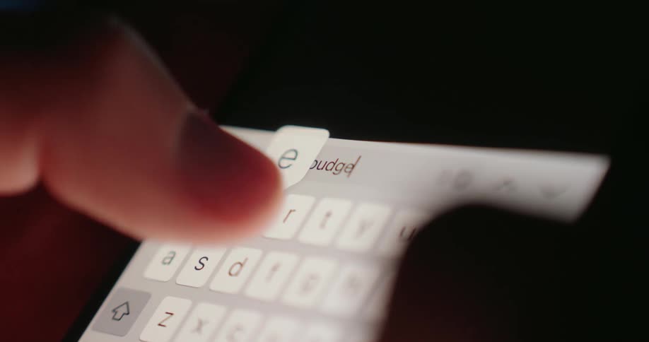A person uses their thumbs to search the word budget on the phone