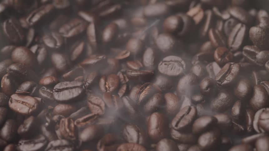 Steam rises from the pile of coffee beans