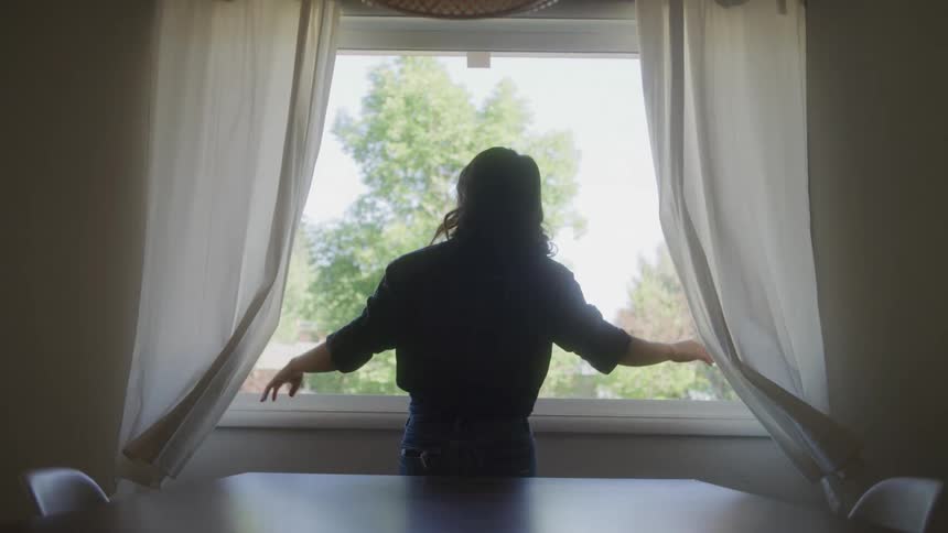 Woman opening the curtain in the window