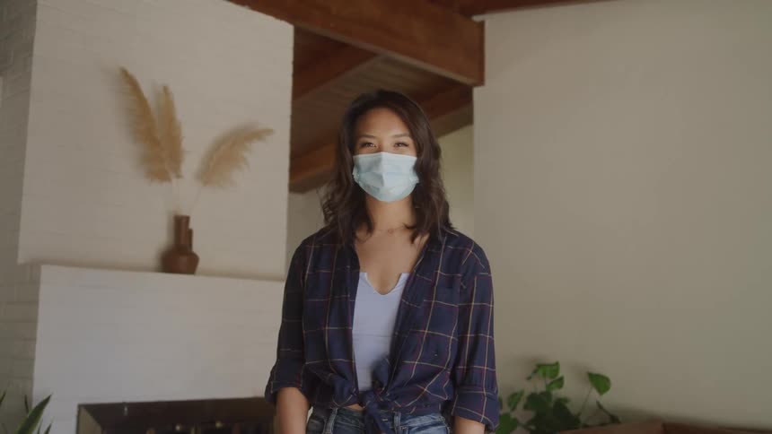 A woman standing in a living room wearing a mask