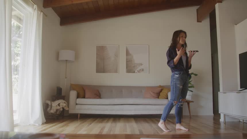 A woman walking around the room while talking on the phone