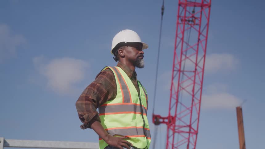 A man stands outside in front of the construction crane