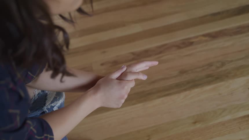 A woman sitting and rubbing her hands looking worried