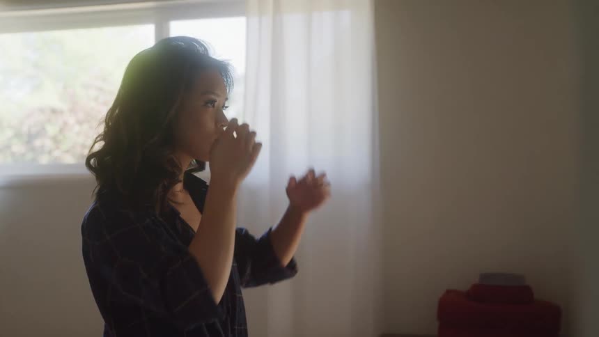 A woman in a bedroom fixing her hair