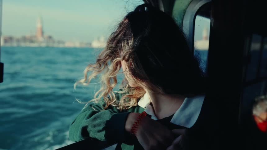 Young woman looks out boat window toward the water