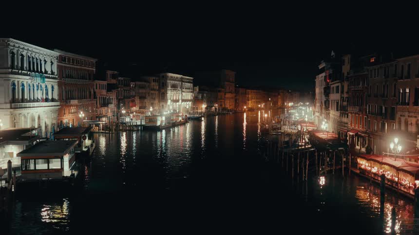 Night view of a venice canal lit by warm reflections and historic buildings