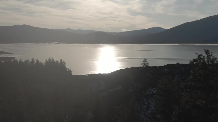 A forest and a large lake with mountains in the background