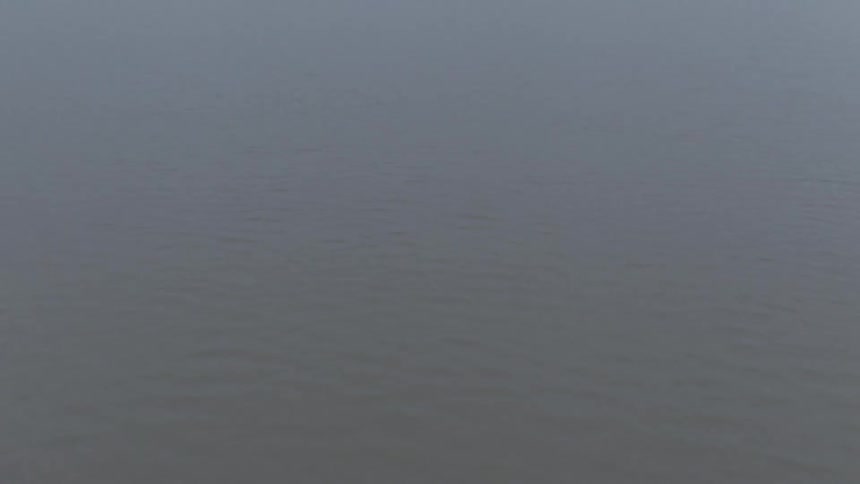 Aerial shot of a river with mountains on the horizon on a cloudy day
