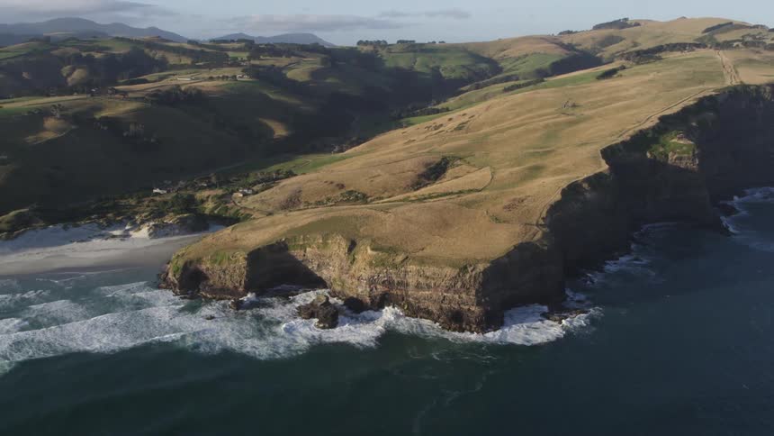 Ocean waves crash into the base of a cliff