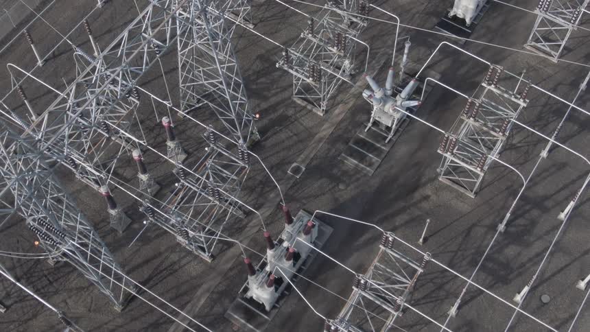An aerial view of an electrical substation with interconnected power lines transformers and metal structures