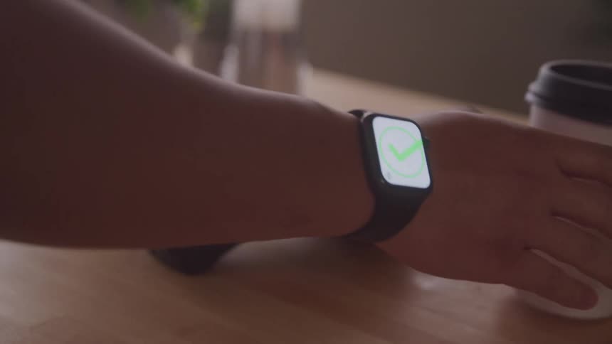 A person uses a smartwatch to make a contactless payment before picking up coffee