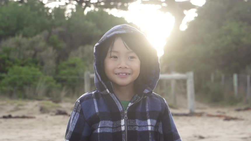 A young kid in a hoodie outside in the sun