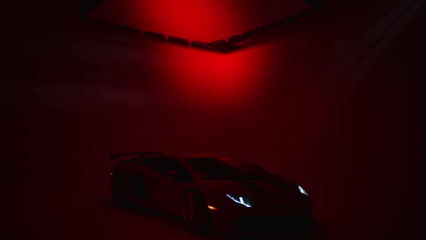 Lamborghini in a studio with a red light and headlights on