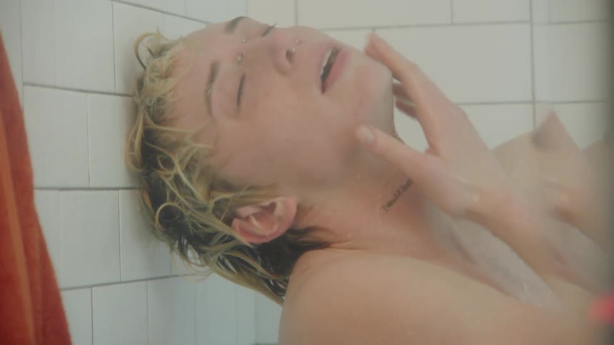 Man with tattoo taking a shower and with both hands on his face
