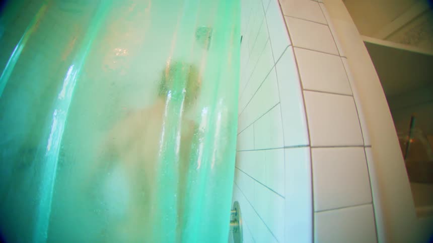 A person dances wildly behind a foggy shower curtain in a brightly lit bathroom