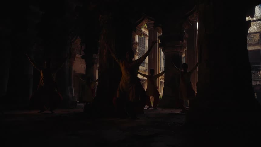 A group of people practicing martial arts inside an open building with the surroundings appearing dim despite it being midday