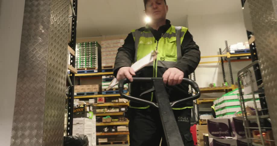 The worker is pulling a pallet jack