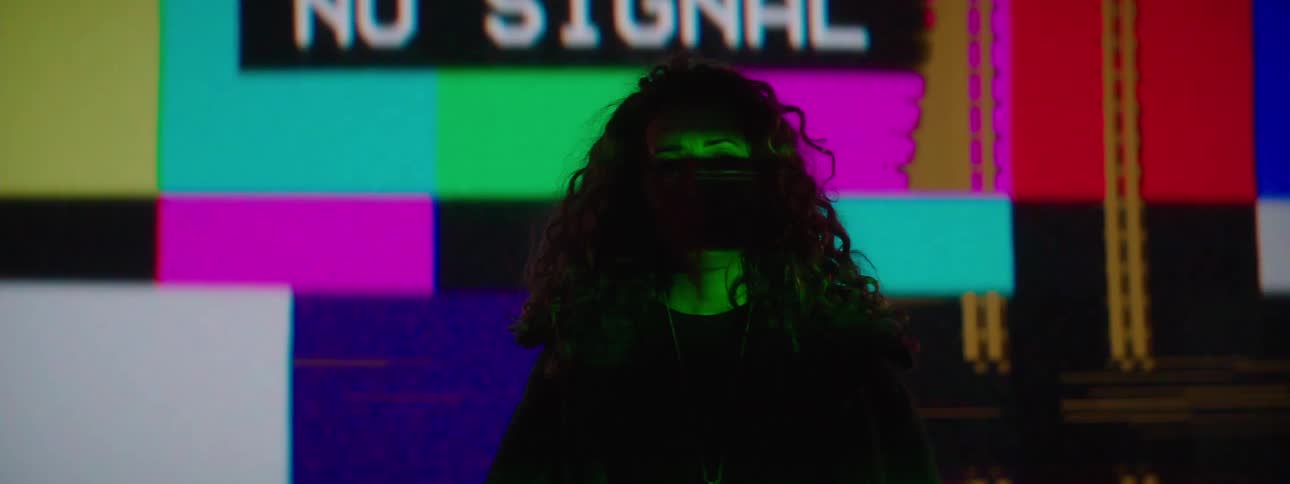 A woman is standing in front of a flashing projection on the wall