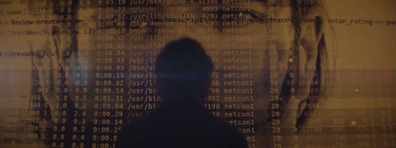 Silhouette against code and face projection evoking digital surveillance