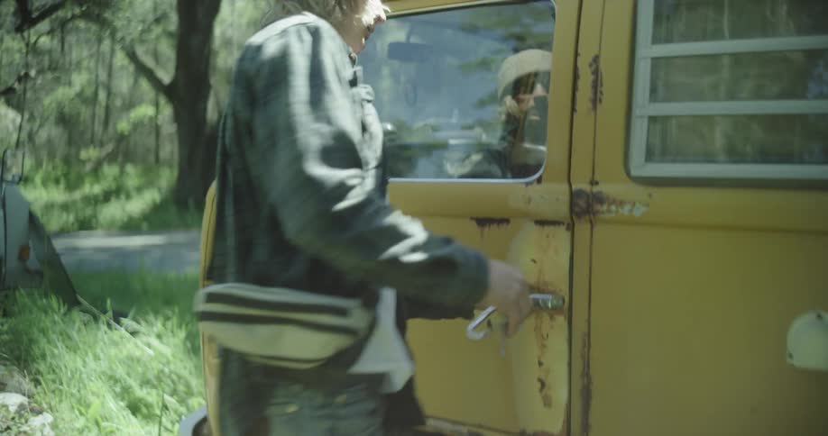 Man closing the door of a kombi van parked outdoors