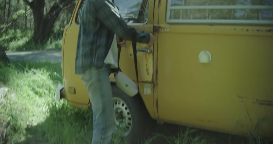 A man holding a purse starts to get into an old van