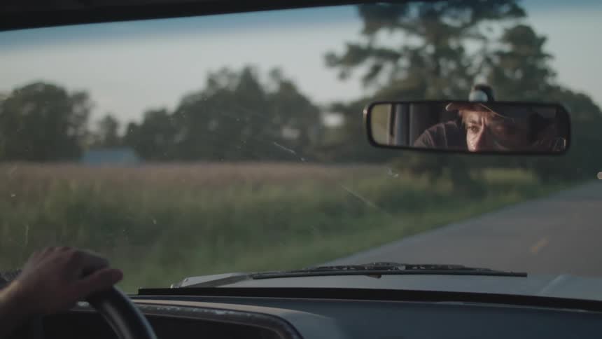 A man is driving his car down a rural road