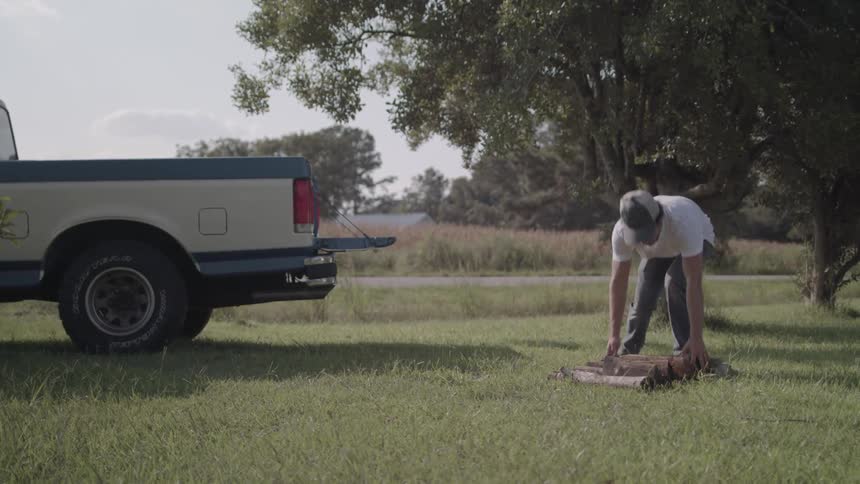 A man loads logs into his pickup truck
