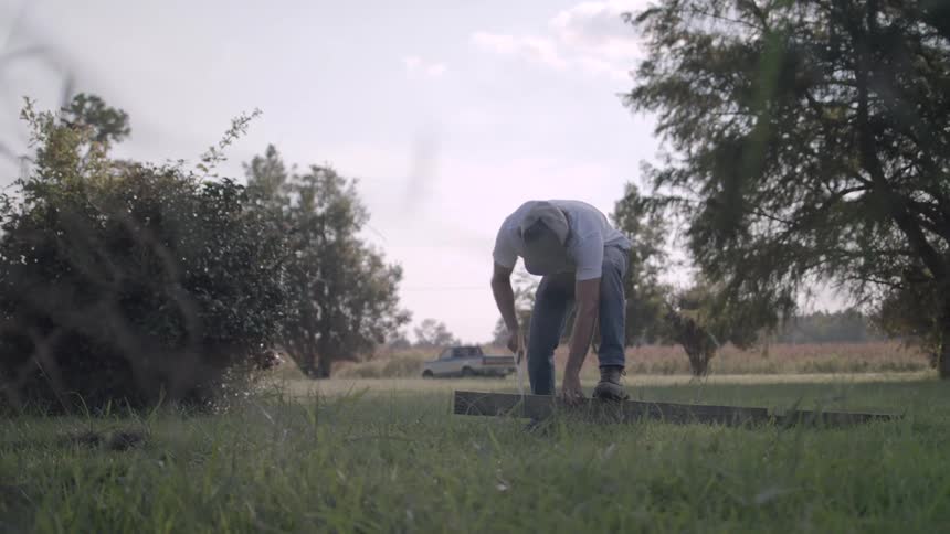 A man is using a saw to cut a post