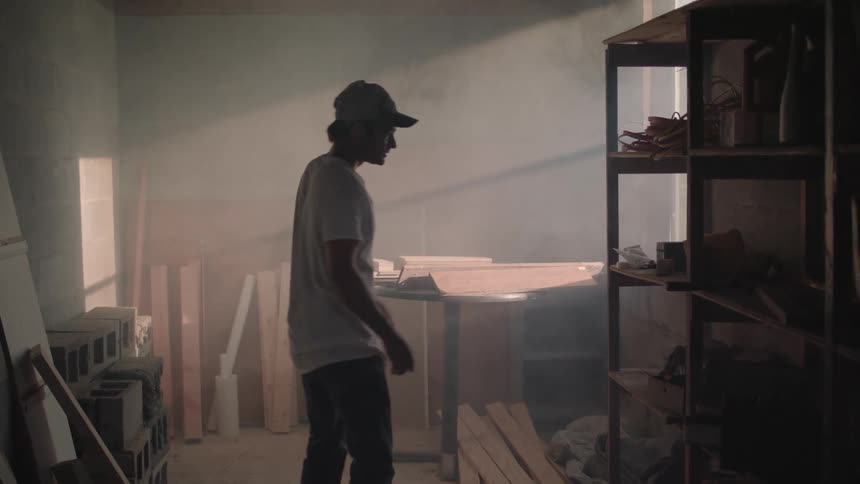A man walks into a room full of tools and lumber
