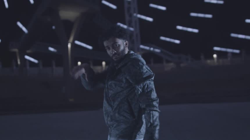 A man dances in a huge dome lined with ceiling lights at night