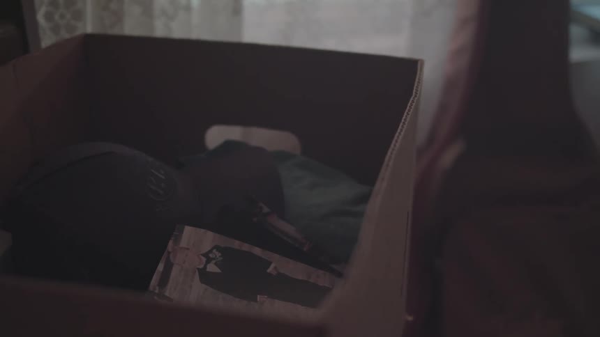 A cardboard box holds personal items and a photo hinting at packing or unpacking memories