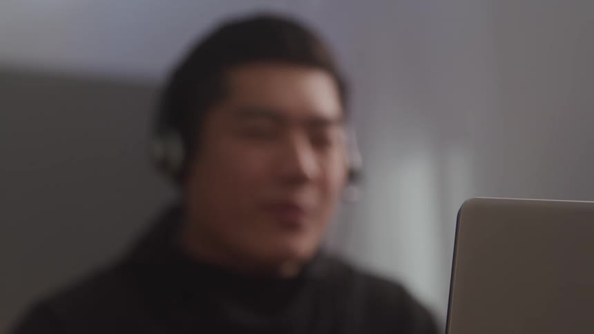 Man with headset talking in front of a laptop