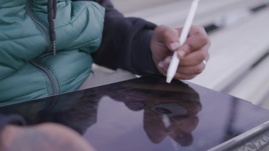 Hand holding a digital pen and painting on a tablet