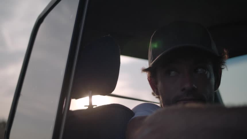 Man wearing a cap inside a moving vehicle
